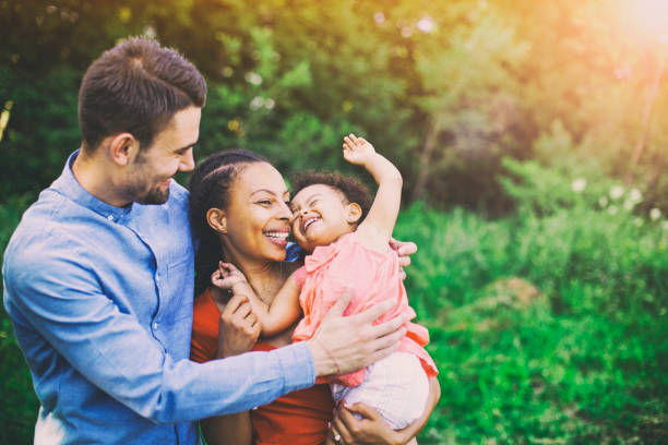 Family Walking In Field Carrying Young Baby Girl Family Walking In Field Carrying Young Baby Girl multiracial person stock pictures, royalty-free photos & images