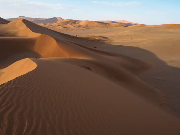 istock Walking on natural curved ridge line through wind blow pattern of rusty red sand dune with soft shadow on vast desert landscape horizon background, Sossus, Namib desert 843910108