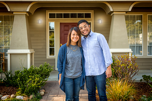 Stock photo of a young, attractive Asian American couple outside their home