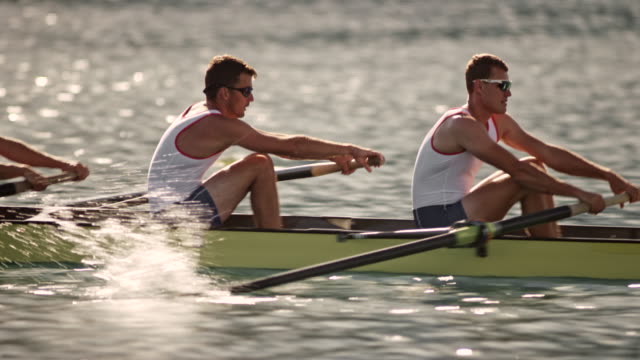 TS Four male athletes rowing on a lake