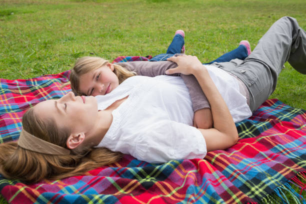 istock Relaxed mother and daughter lying at park 843921648