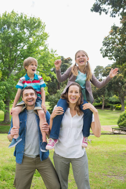 istock Happy parents carrying kids on shoulders at park 843921918