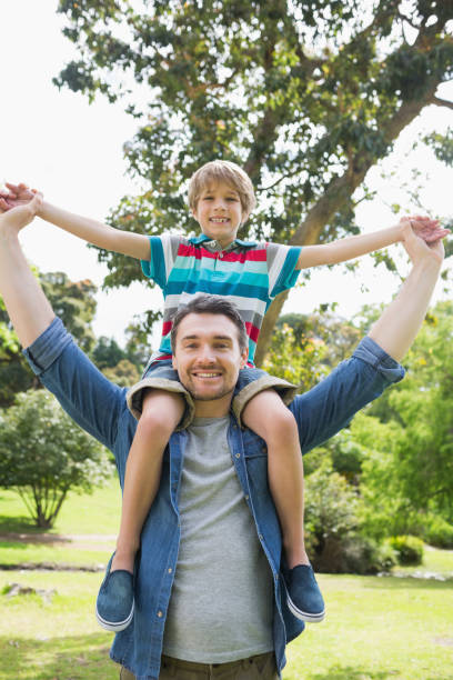 istock Father carrying boy on shoulders in park 843924126