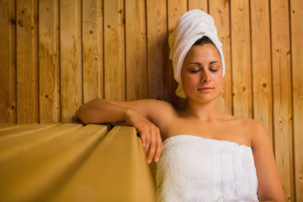 Calm woman relaxing in a sauna wearing white towels