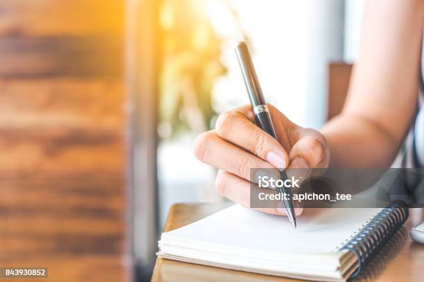 Womans Hand Is Writing On A Blank Notepad With A Pen On A Wooden Desk Stock Photo - Download Image Now