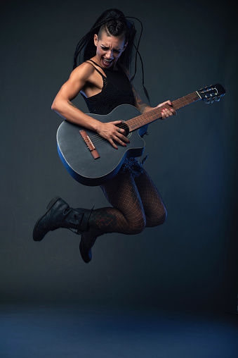 Female hard rock singer jumping with guitar in her hands