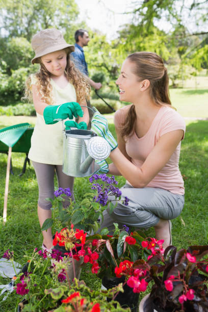 istock Mother with daughter watering plants 843941734