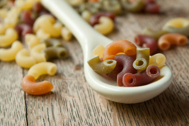 colorful pasta on a spoon on wooden background