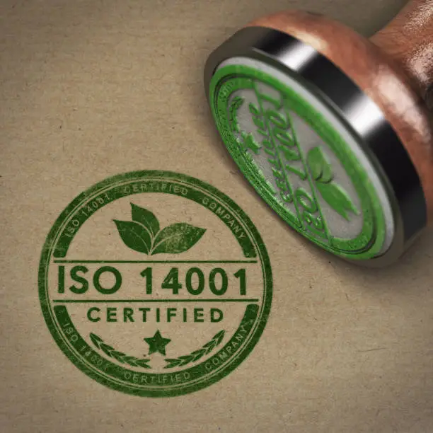 3D illustration of a rubber stamp with the text ISO 14001 over brown cardboard background