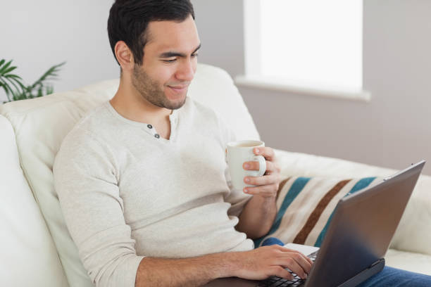 istock Calm attractive man drinking coffee while working on his laptop 843942732
