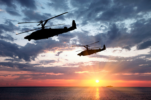 Two military helicopter on a sunset background.