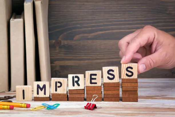 Photo of Impress concept. Wooden letters on the office desk, informative and communication background