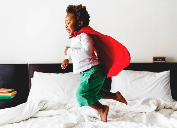 istock African descent kid jumping on the bed with robe 843966272