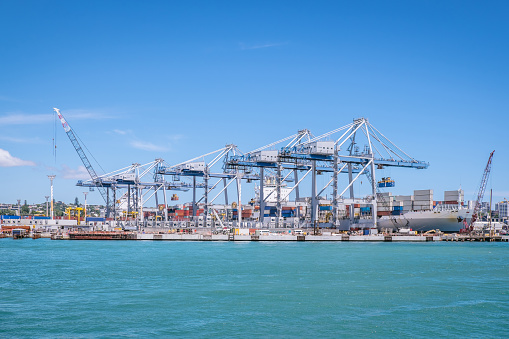 Auckland port with shipping containers, cranes and ship providing transportation for imports and exports in New Zealand, NZ