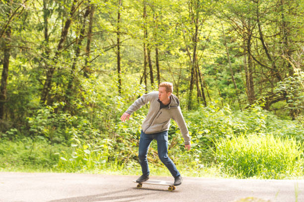 red-haired male skateboards through forest - hat trick imagens e fotografias de stock
