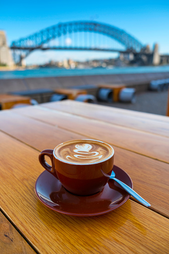 A cup of coffee with the Sydney Harbour Bridge beyond.