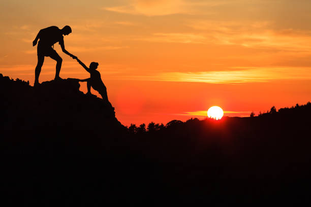 Teamwork couple helping hand trust in inspiring mountains stock photo
