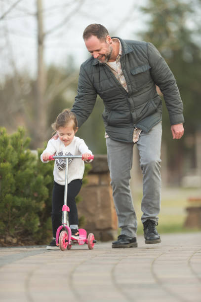 istock Dad helping young daughter learn to ride scooter 843983318