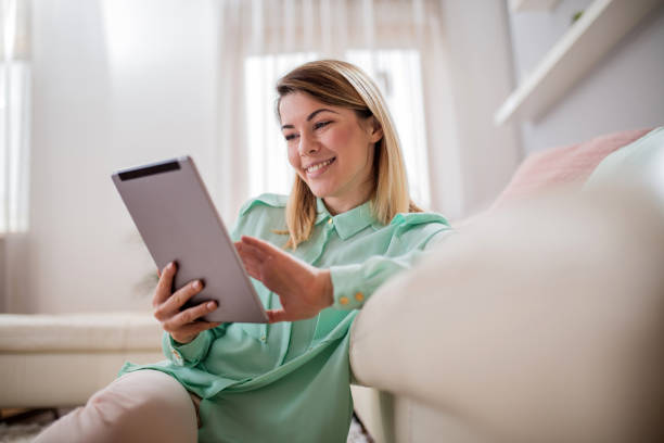 istock Young beautiful woman reading an e-mail on e-reader at home. 843989516