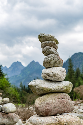 Stones balance, hierarchy stack over cloudy sky in mountains. Inspiring stability concept on rocks.