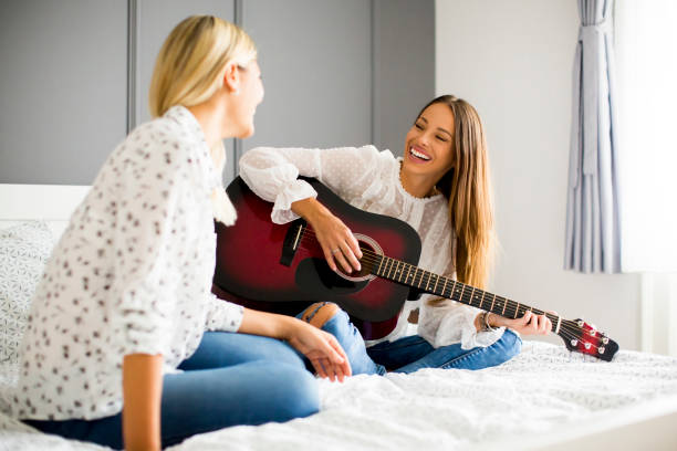 istock Two young women with guitar on bed 844008928