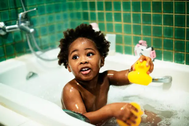 Photo of African descent kid enjoying bath tub