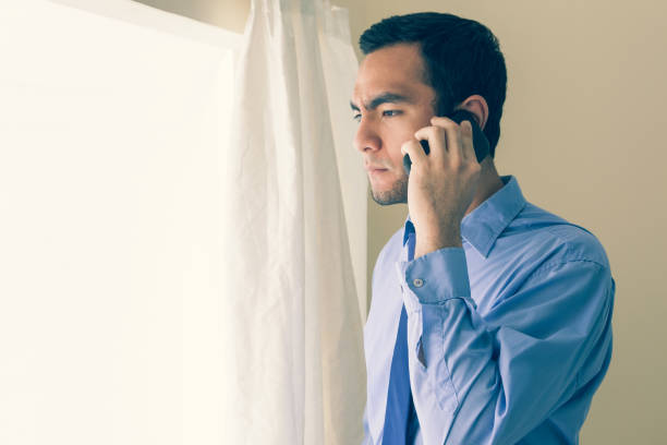 istock Irritated man calling someone with a mobile phone and looking out the window 844013030