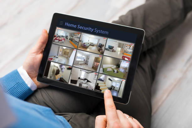 Man looking at home security cameras on tablet computer stock photo