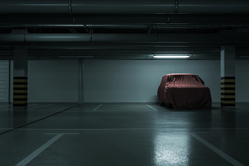 Red covered vintage car in empty underground parking background with copy space
