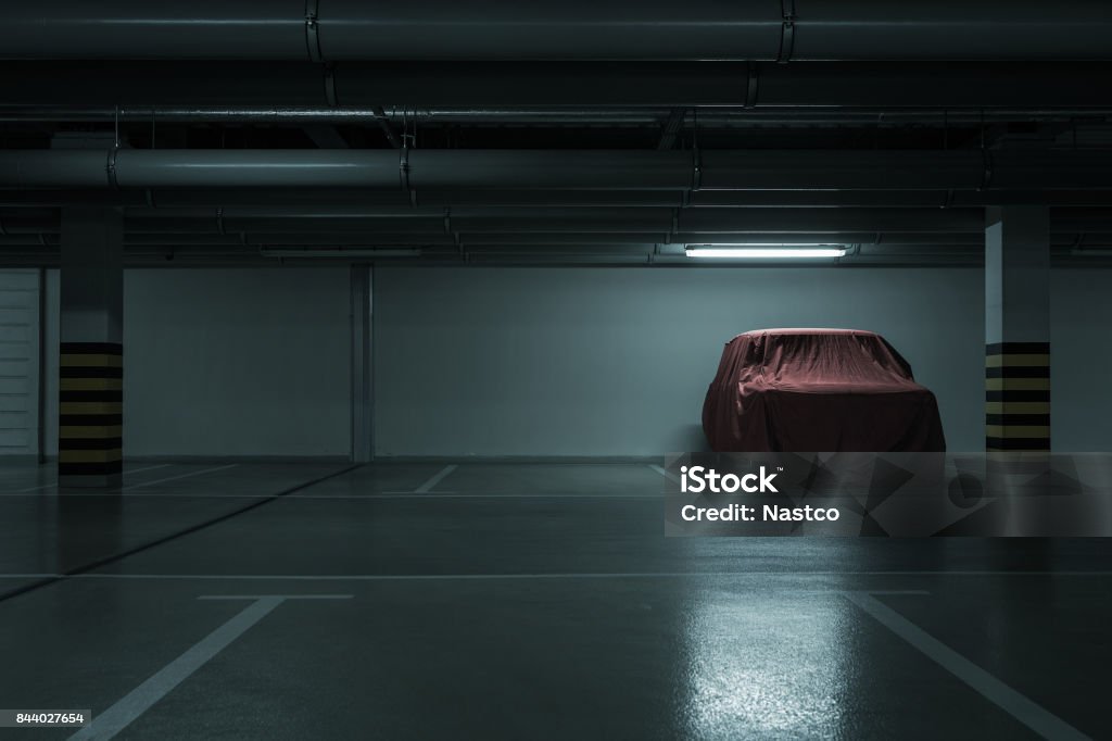 Underground parking background Red covered vintage car in empty underground parking background with copy space Car Stock Photo