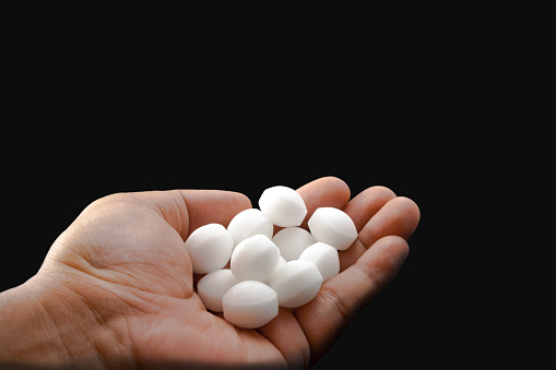 Moth balls on the male hand.