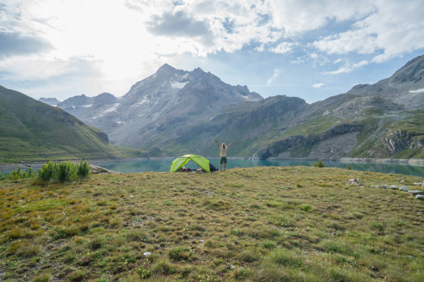 istock Young woman standing beside tent arms outstretched 844031454
