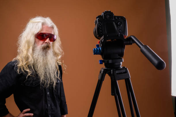 istock Studio shot of senior bearded man wearing red sunglasses while vlogging against colored background 844039232