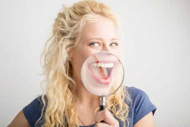 Photo of Woman showing her smile through magnifying glass
