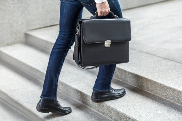 Businessman with briefcase in hand walking up on stairs.