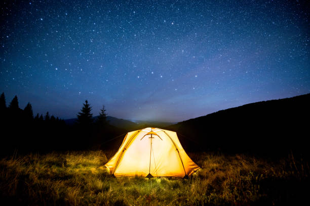 istock Glowing camping tent in the night mountain forest under a starry sky 844050242