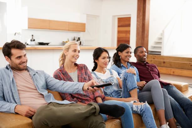 istock Group Of Friends Sitting On Sofa Watching Television Together 844053972