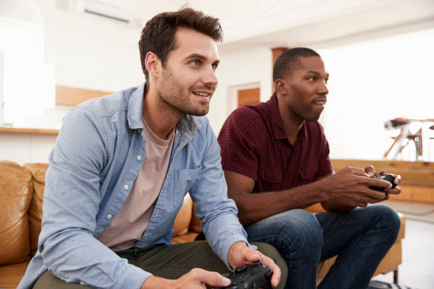 istock Two Male Friends Sitting On Sofa In Lounge Playing Video Game 844054170