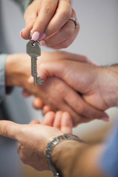 istock Estate agent giving house key to customer while shaking hands 844057208