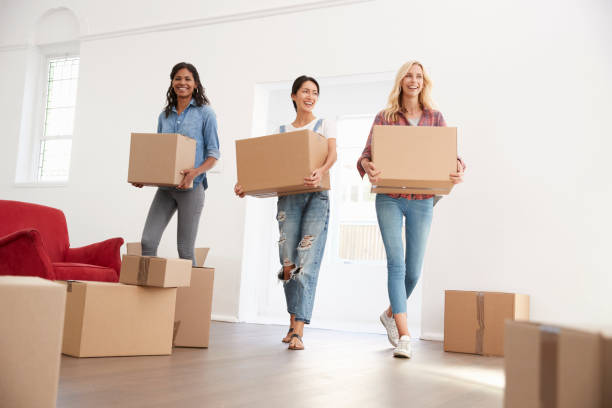 Three Female Friends Carrying Boxes Into New Home On Moving Day Three Female Friends Carrying Boxes Into New Home On Moving Day roommate stock pictures, royalty-free photos & images