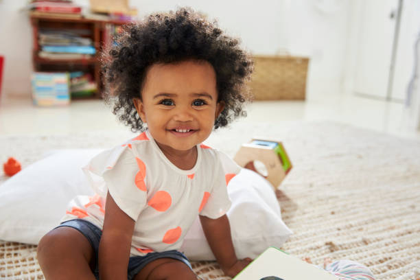 porträt von happy babymädchen spielen mit spielzeug im spielzimmer - kleinstkind stock-fotos und bilder