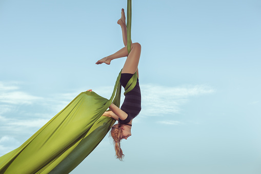 Woman the equilibrist flies in the sky on a hammock.