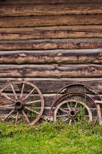 An old wooden wheel against a log building