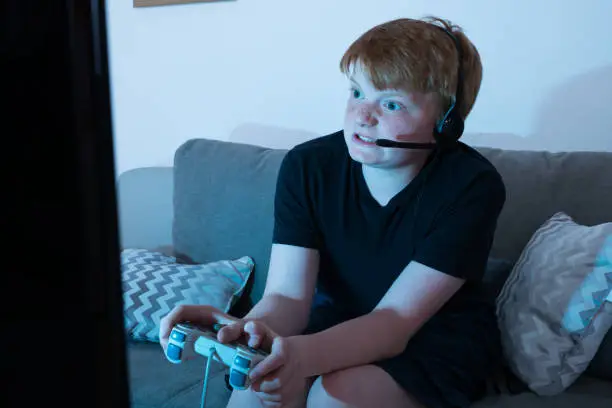 Angry Boy Sitting On Sofa Playing Videogames