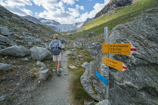Young woman hiking in the European Alps, trail signs.