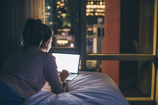 Women at hotel room using laptop.