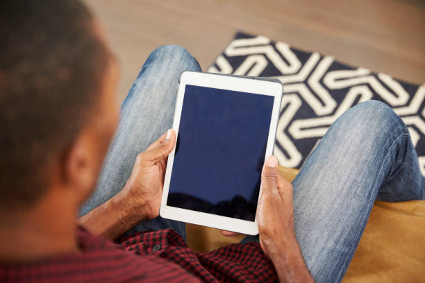 istock Man Sitting On Sofa At Home Looking At Digital Tablet 844063854