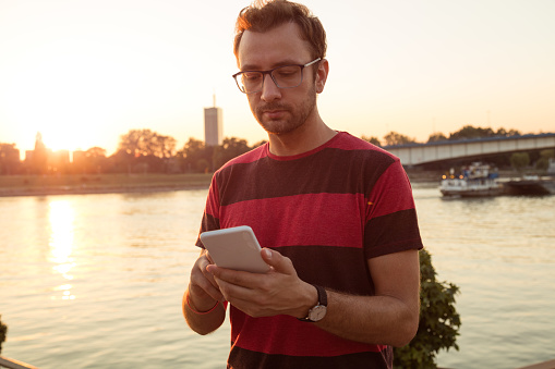 Modern guy using cellphone outdoors.