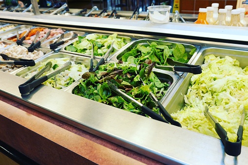 A counter or table in a restaurant or supermarket on which a variety of prepared salads and salad ingredients are displayed for self-service.