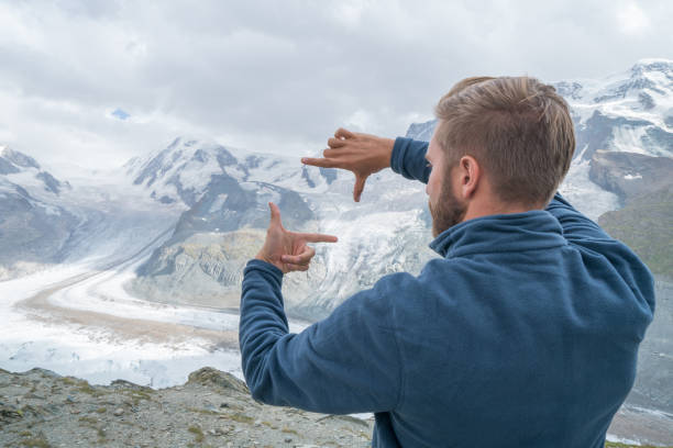 low angle view of handsome young man standing with open arms in beautiful mountains, Alps